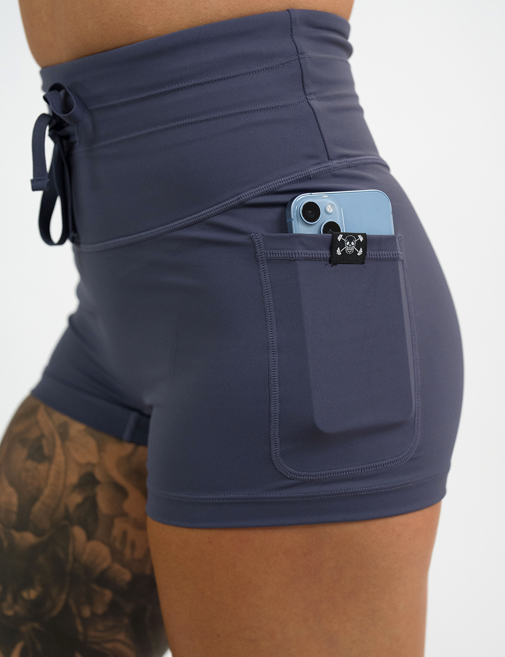 close up of the 2.5 inch omni light purple shorts with a phone in its pocket against a white background