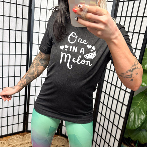 model wearing a black unisex shirt with the saying "one in a melon" on it