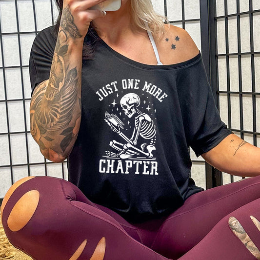 model wearing a black slouchy tee with the saying "Just One More Chapter" on it