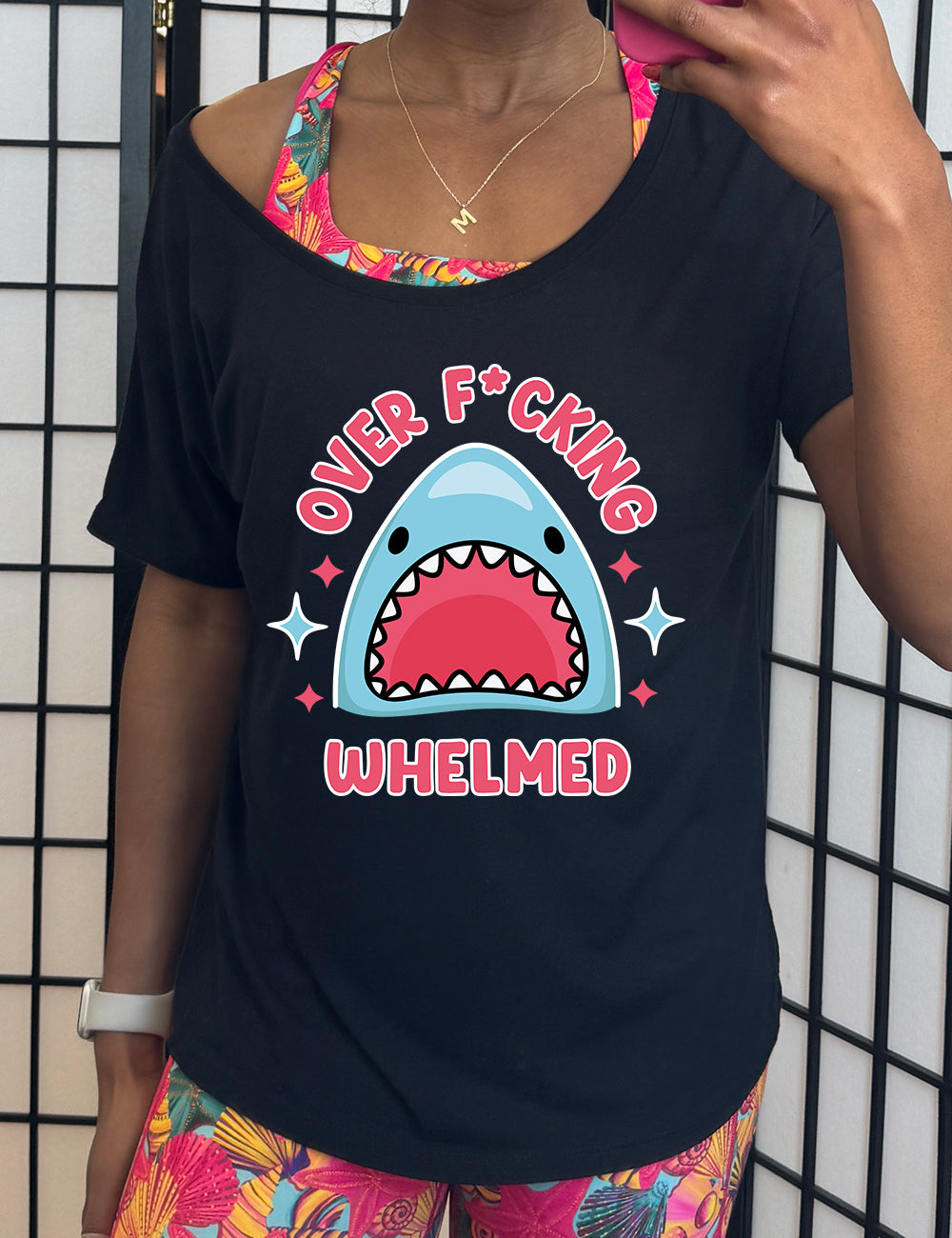 black slouchy tee with the graphic of a shark's head with mouth wide open, and the words around the graphic saying "over f*cking whelmed" and a few stars on the sides
