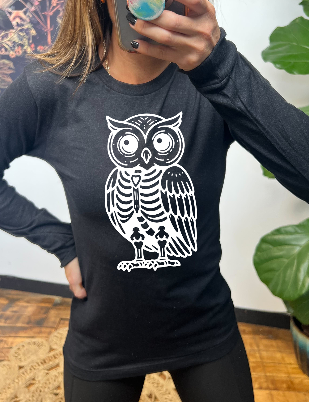 heather black long sleeve tee with the large graphic of an owl with part of its body in skeletal form, with a little heart in the middle of its ribcage