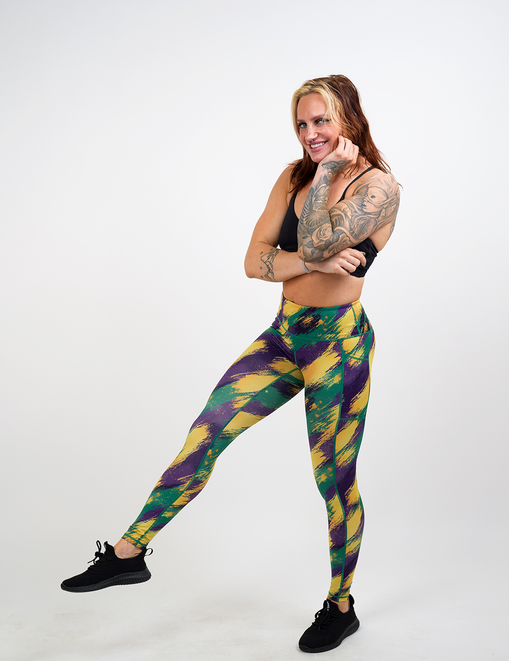 model wearing the painted parade leggings, green yellow and purple striped pattern, against a white background