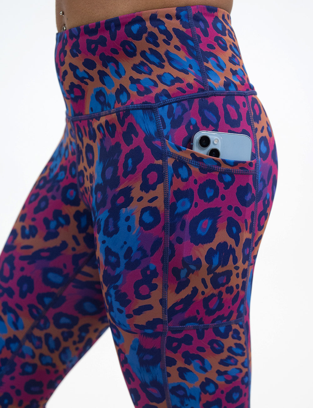 close up of the red, yellow, and blue cheetah print leggings with a phone in its pocket