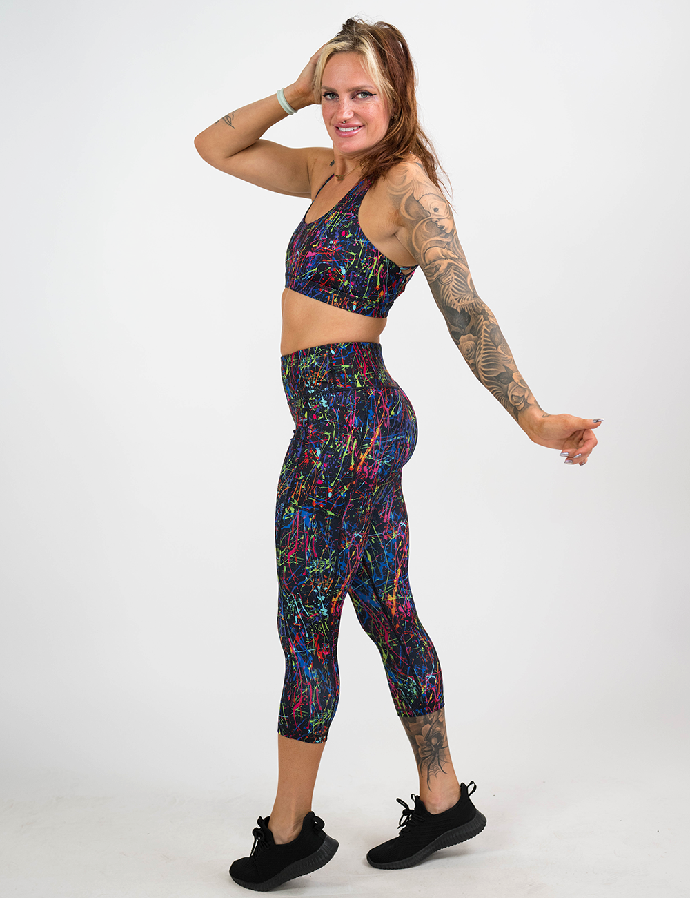 model wearing the rainbow paint splatter capri leggings against a white background