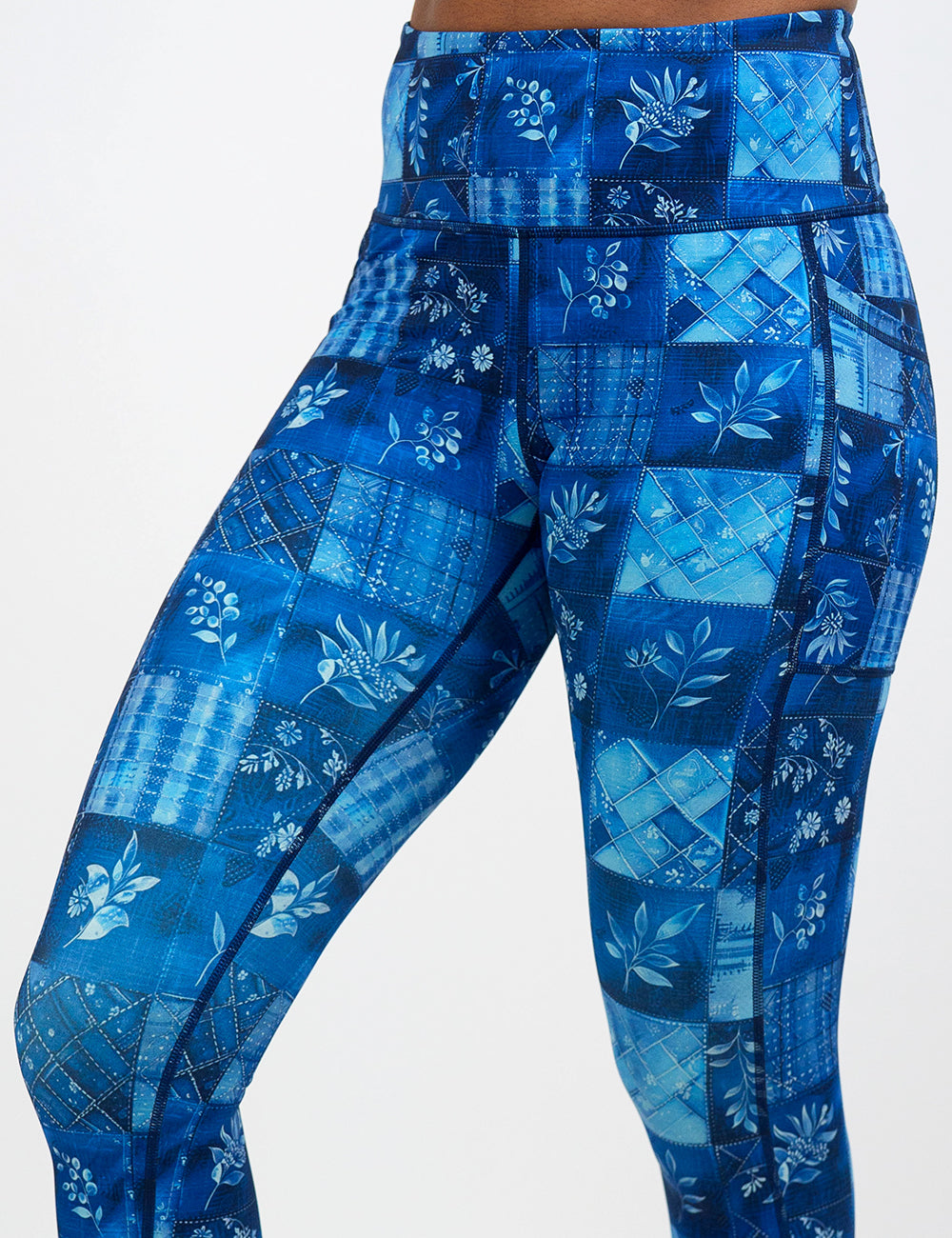 close up of the blue patch work pattern with plant designs leggings against a white background