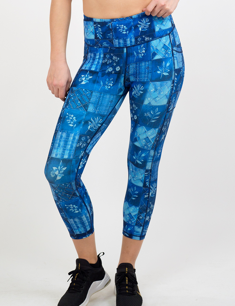 blue patch work pattern with plant designs capri leggings against a white background