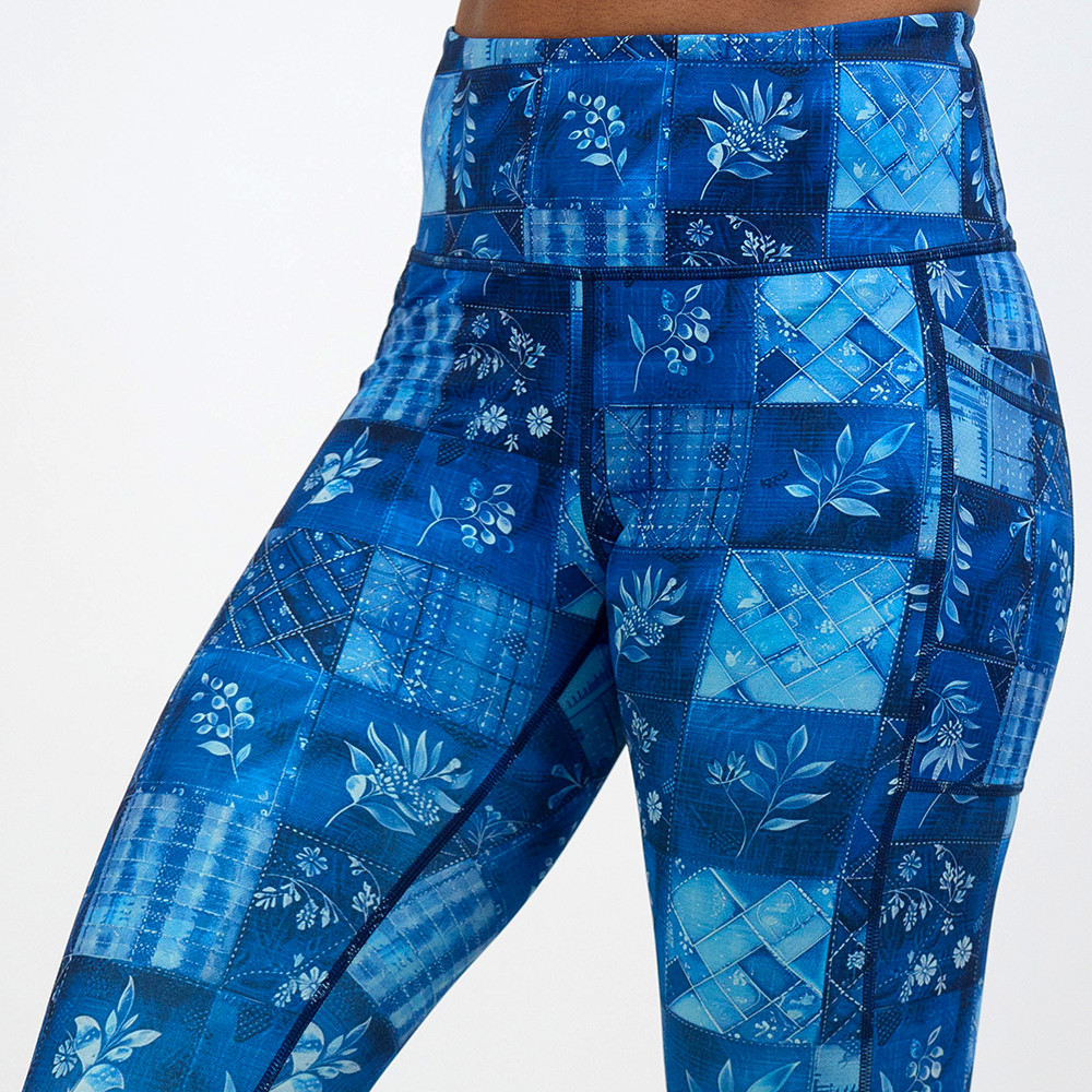 close up of the blue patch work pattern with plant designs leggings against a white background
