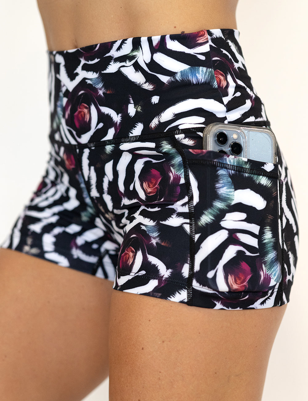 close up of the blue, pink, white petal design 2.5 inch shorts with a phone in its pocket