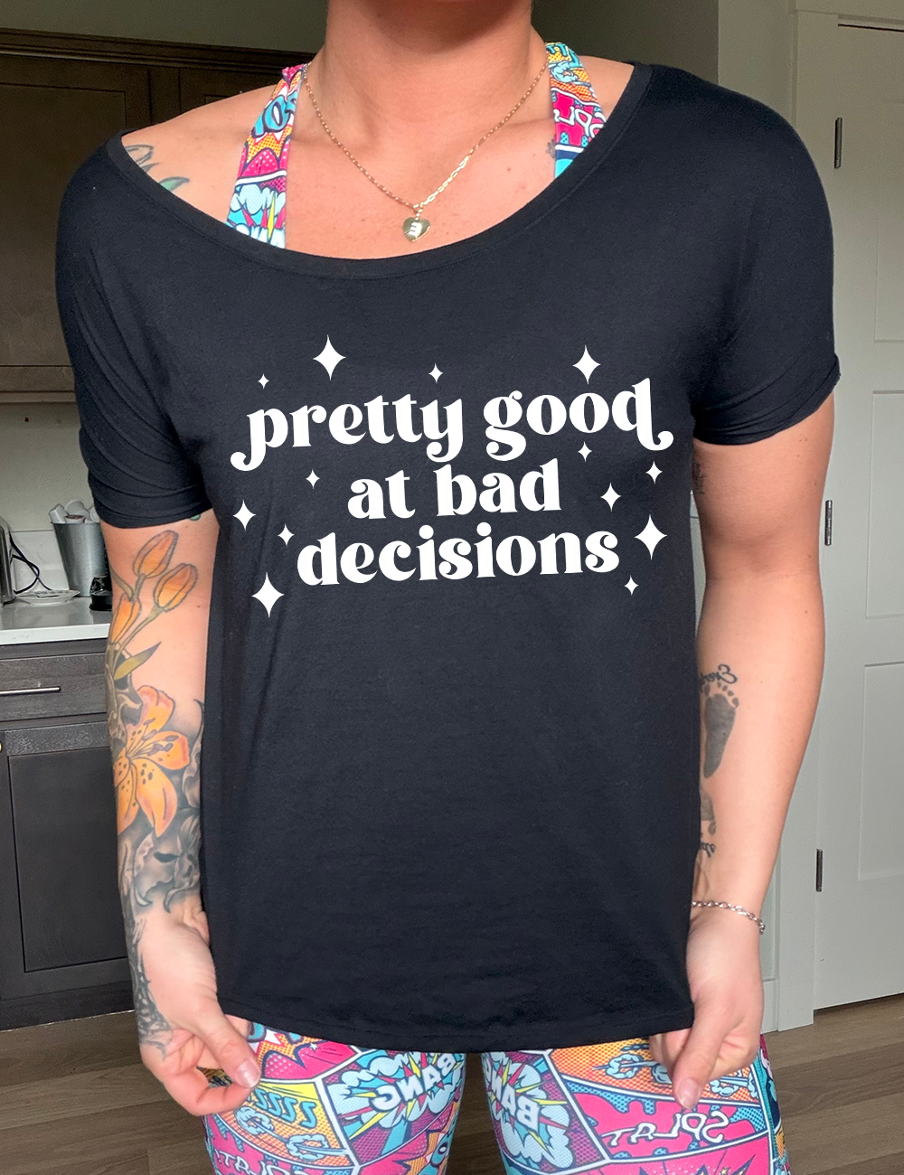 black slouchy tee with the words "pretty good at making bad decisions" on it, with a few little stars scattered around the words