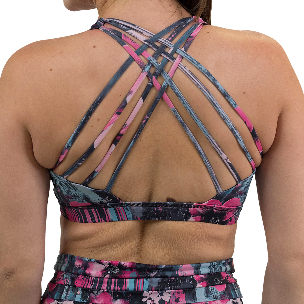 back of the pink flowers against a bold teal and pink striped background pattern butterfly back bra against a white background