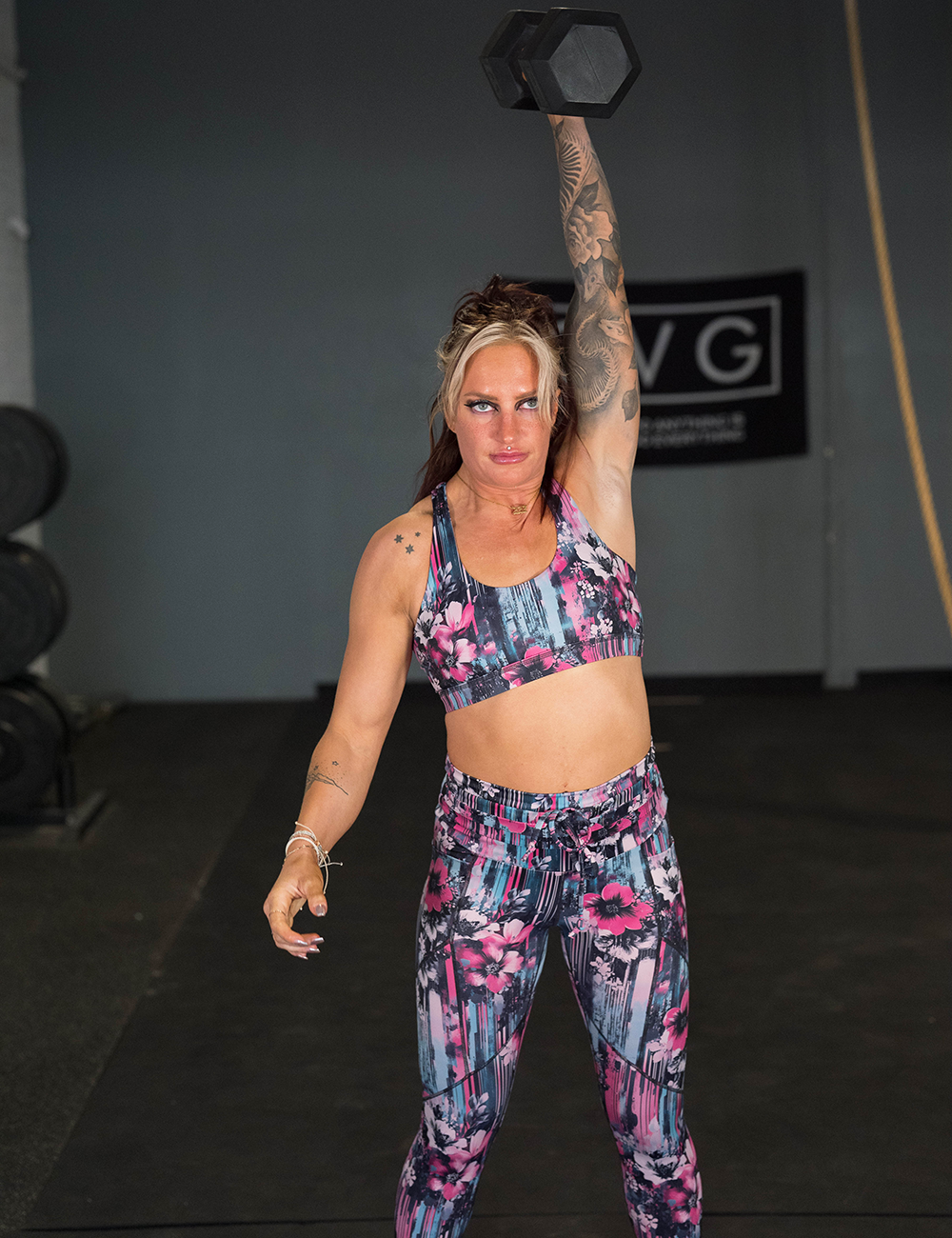 pretty wild pink flower against a teal and pink striped background leggings in the gym lifting weights