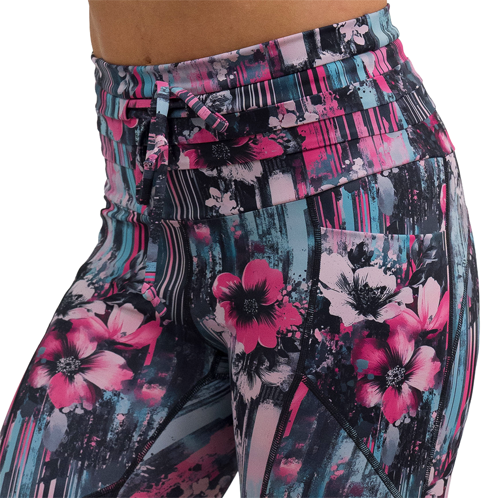close up of the pink flowers against a bold teal and pink striped background pattern leggings against a white background