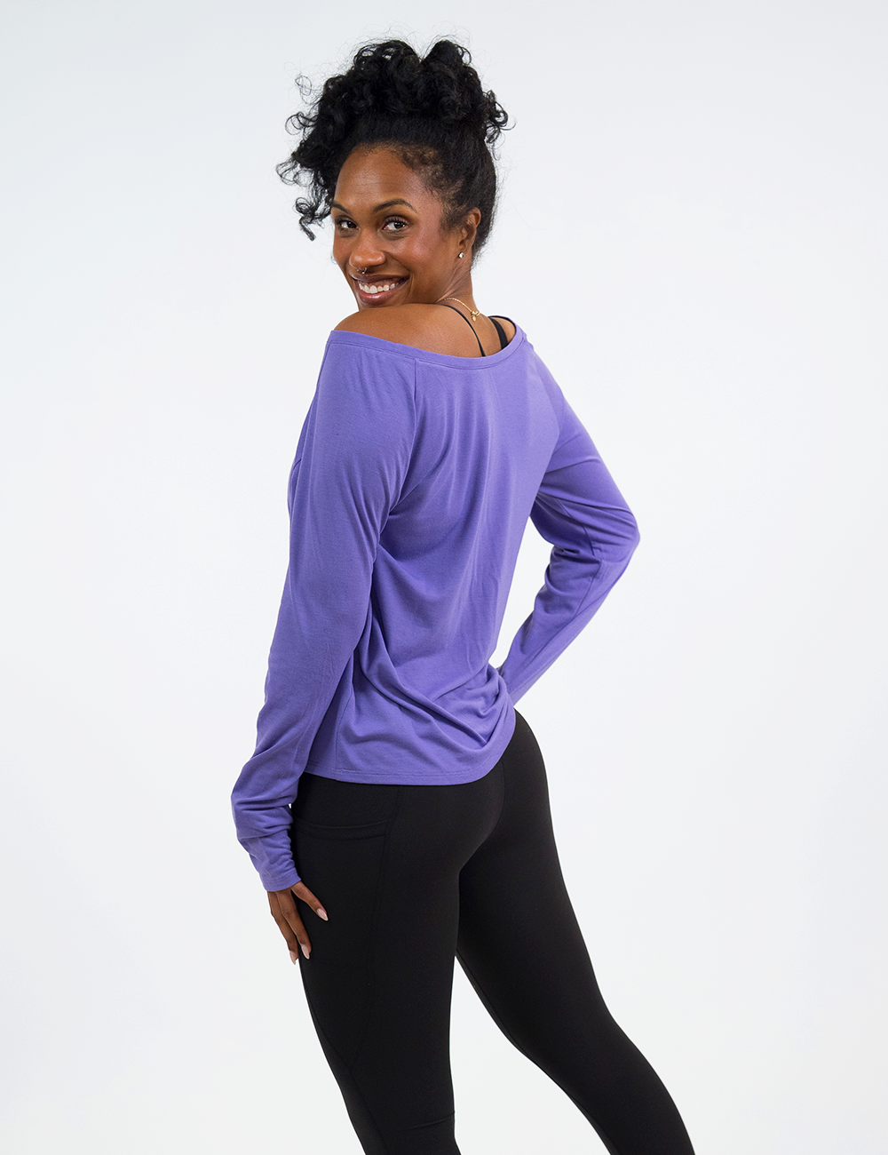 back of the purple long sleeve slouchy tee with black leggings against a white background
