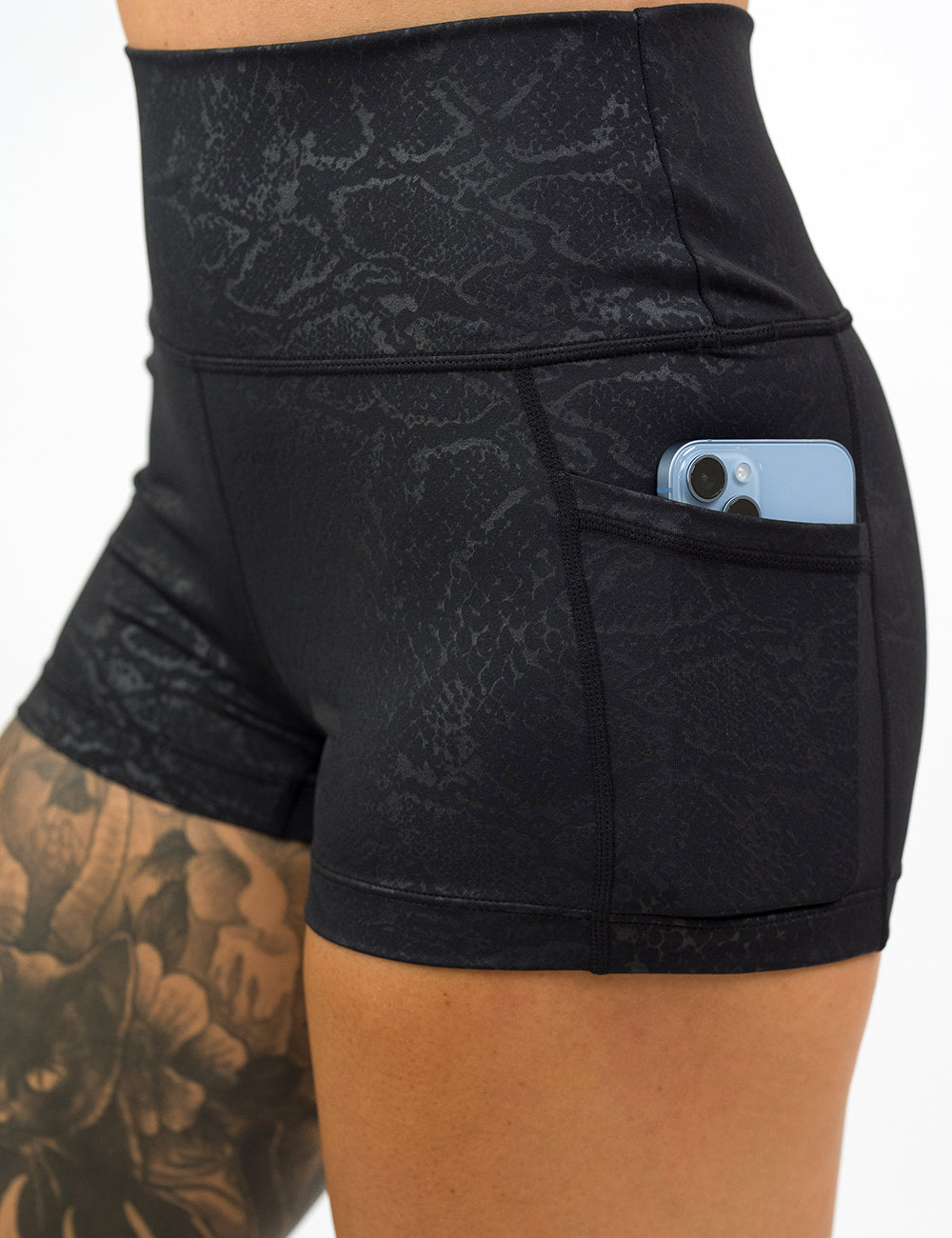 close up of the 2.5 inch dark python print shorts with a phone in its pocket