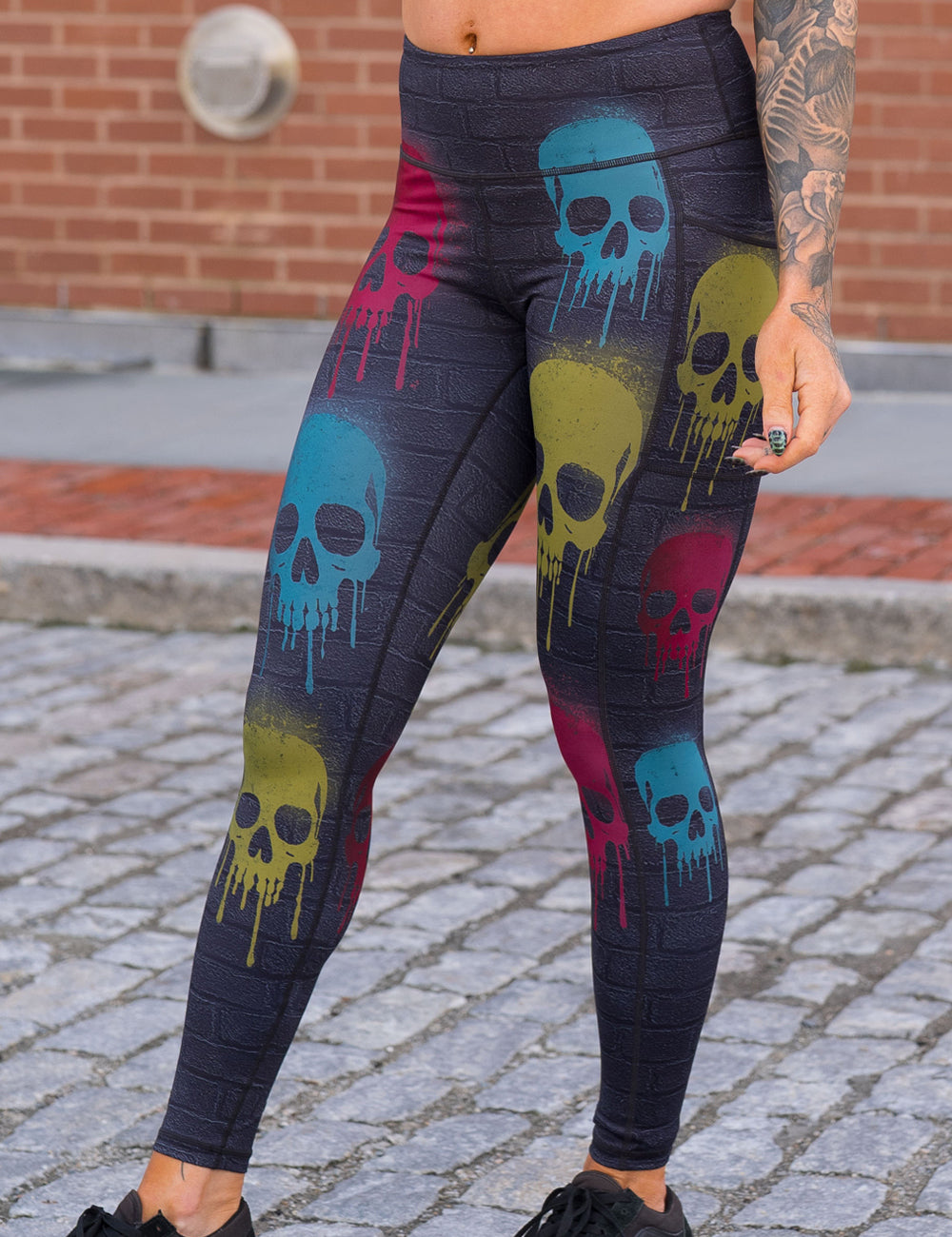 front of the black brick full length leggings with spray painted red, yellow, and blue skulls all over