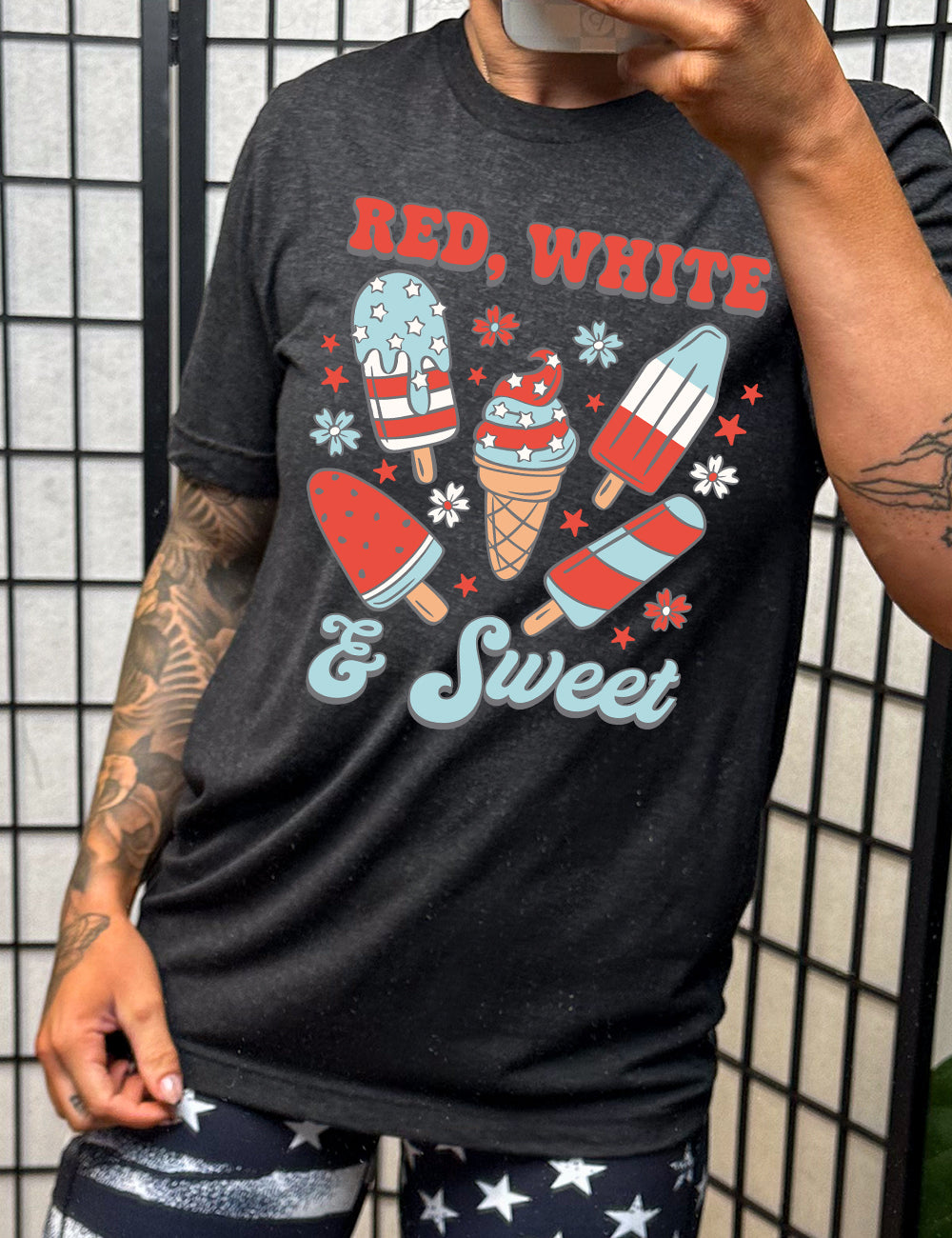 black unisex tee with the words "red, white, & sweet" on it, around the graphics of American flag-designed popsicles and an ice cream comb (5 total treats), and some flowers and stars