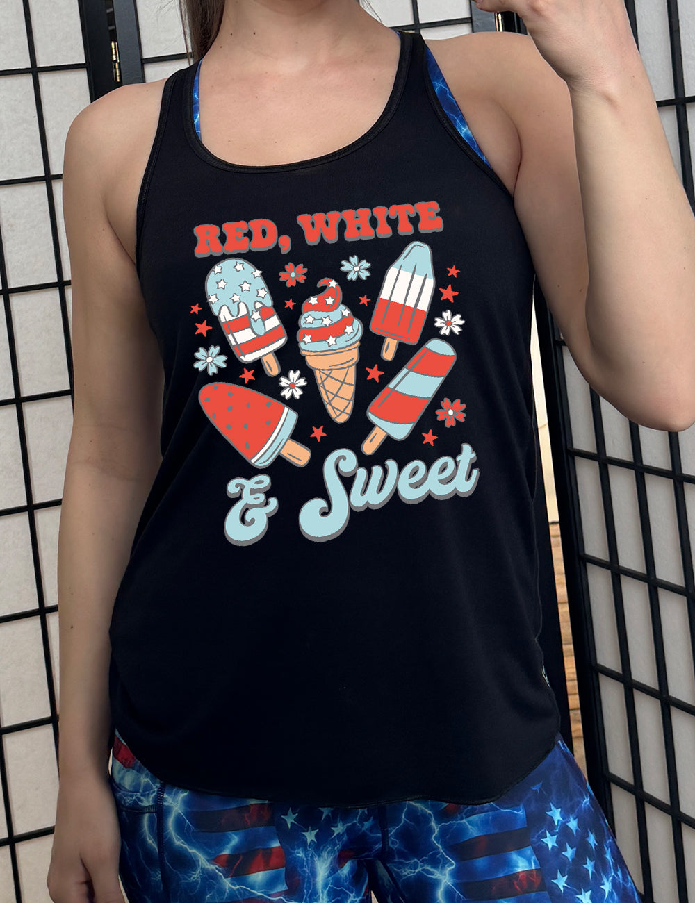 black flowy racerback tank with the words "red, white, & sweet" on it, around the graphics of American flag-designed popsicles and an ice cream comb (5 total treats), and some flowers and stars