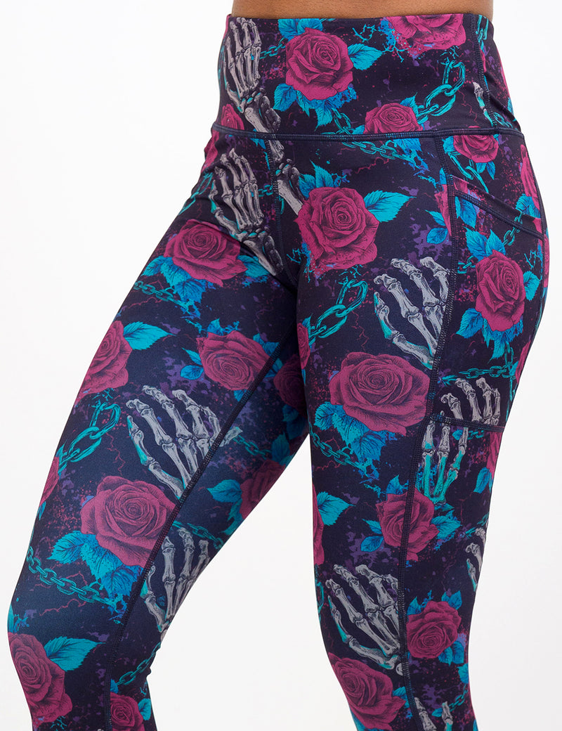 close up of the roses and skeleton hands connected by chain links pattern leggings against a white background