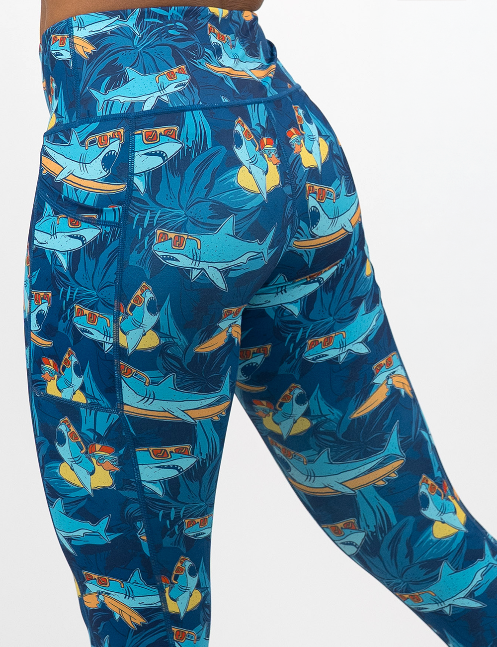back of the cartoon sharks surfboarding with sunglasses leggings against a white background