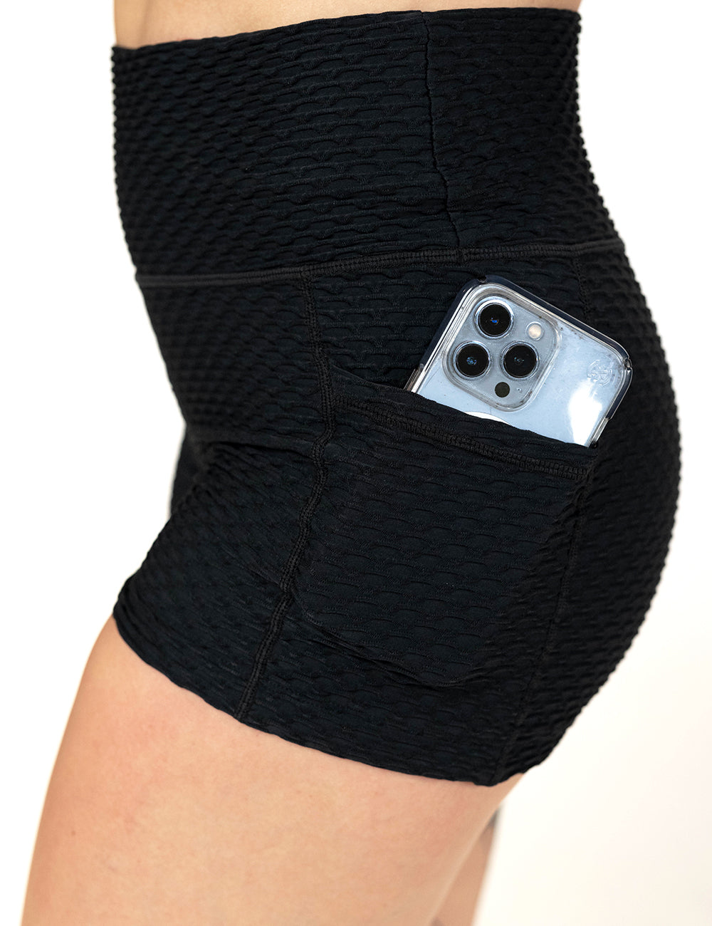 close up of the 2.5 inch black waffled texture shorts with a phone in its pocket