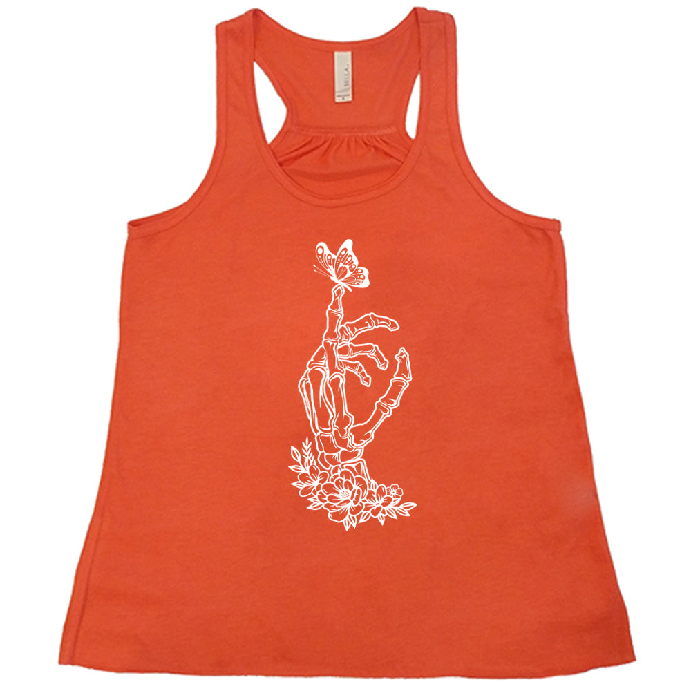 Coral colored flowy tank with a butterfly on a skeletons hand graphic on it
