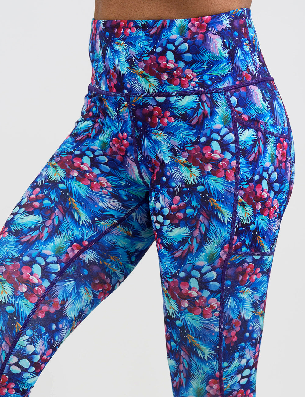 close up of the winter berries among blue leaves leggings against a white background