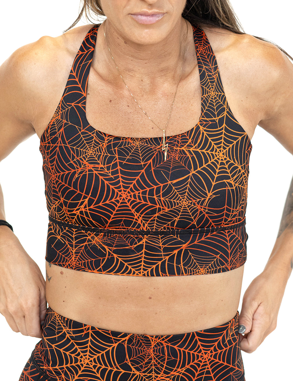 front of the orange spider webs against a black background sports bra against a white background