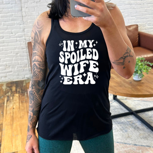model wearing a black racerback tank with the saying "in my spoiled wife era" on it