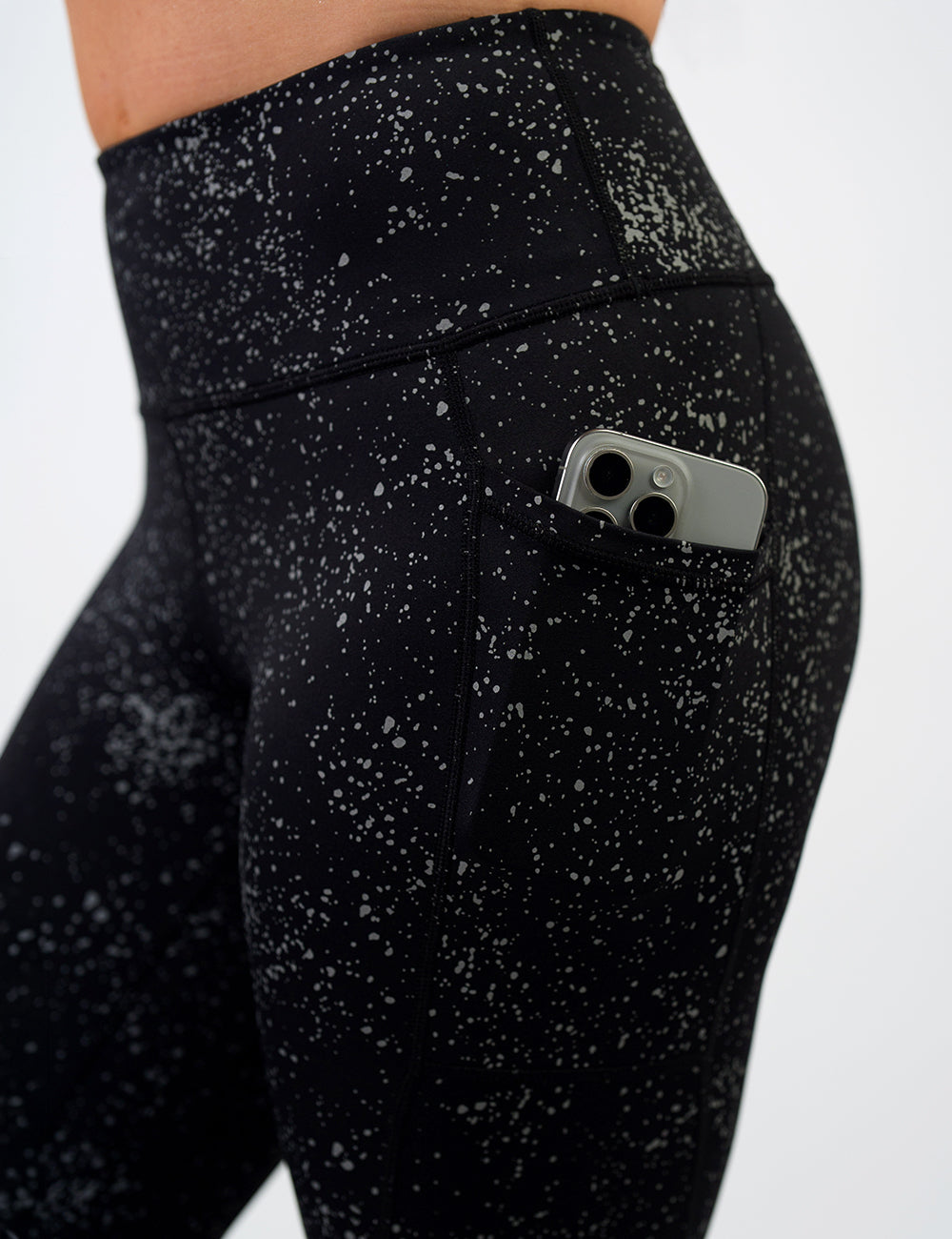 close up of the black spotted reflective leggings with a phone in its pocket