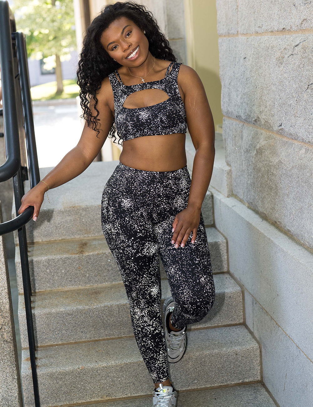model wearing the full length black leggings with reflective spots posing on a staircase with the camera flash on