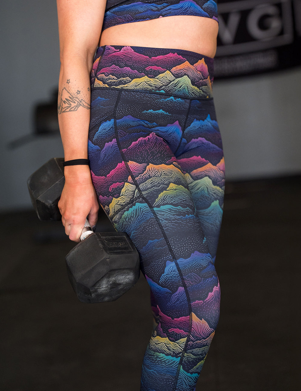 model wearing the colorful mountain print leggings in the gym lifting weights
