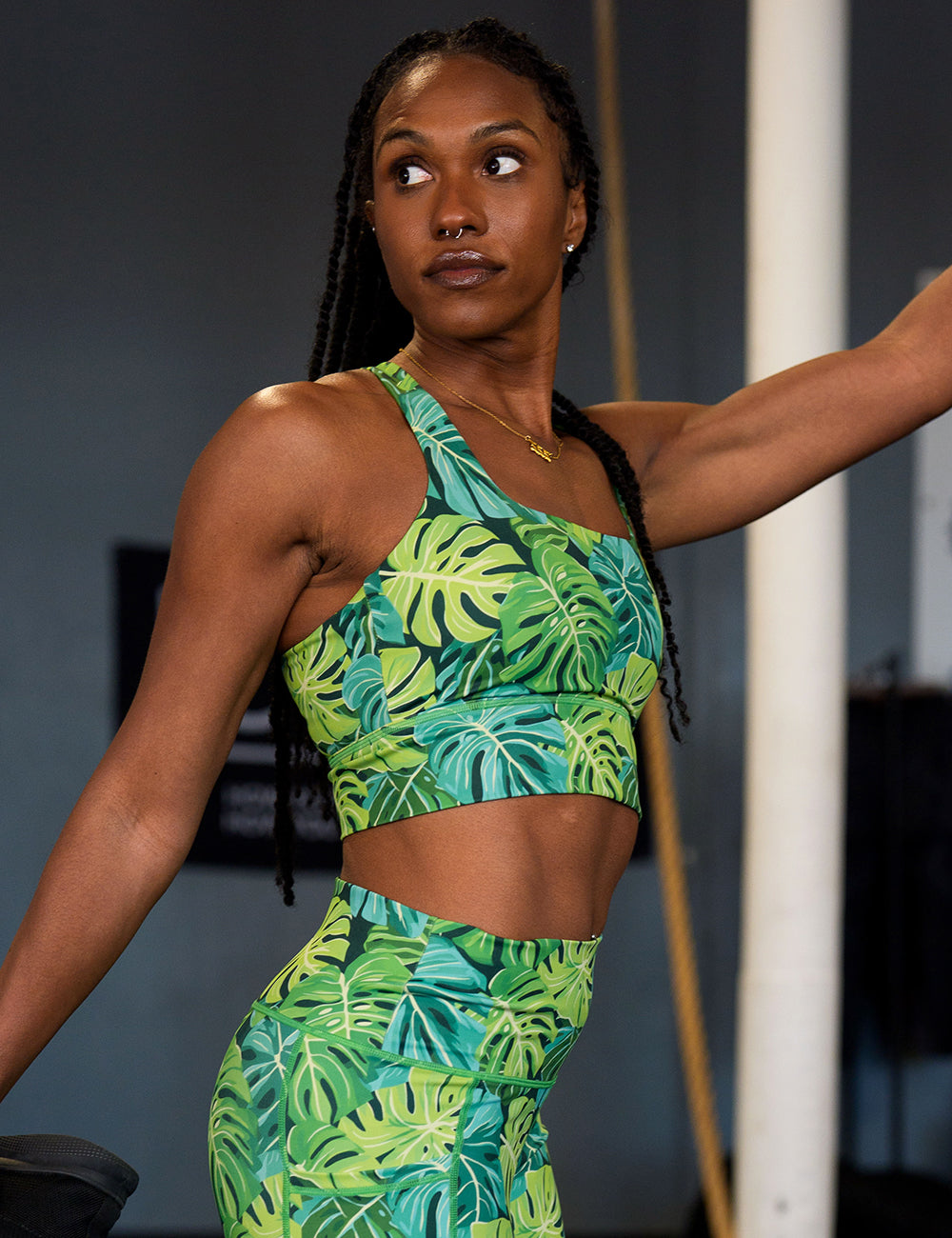 model wearing the green monstera leaves longline bra in the gym stretching