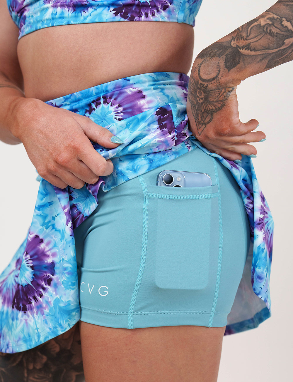 close up of the blue and purple tie dye skirt against a white background being held up to show a phone in the shorts lining pocket