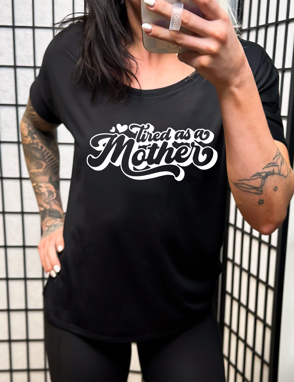 black slouchy tee with the words "tired as a mother' on it, with a couple little hearts at the start