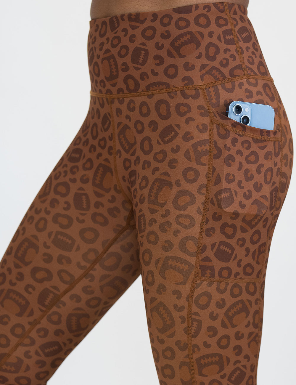 close up of the football themed brown leopard print leggings with a phone in its pocket