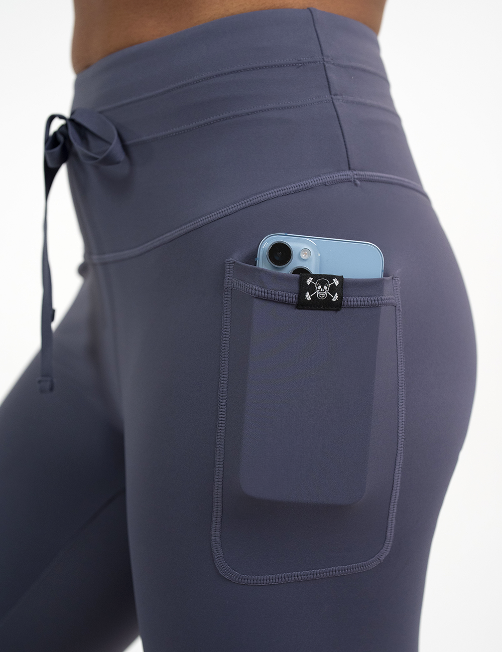 close up of the purple twilight drawstring leggings pocket holding a phone