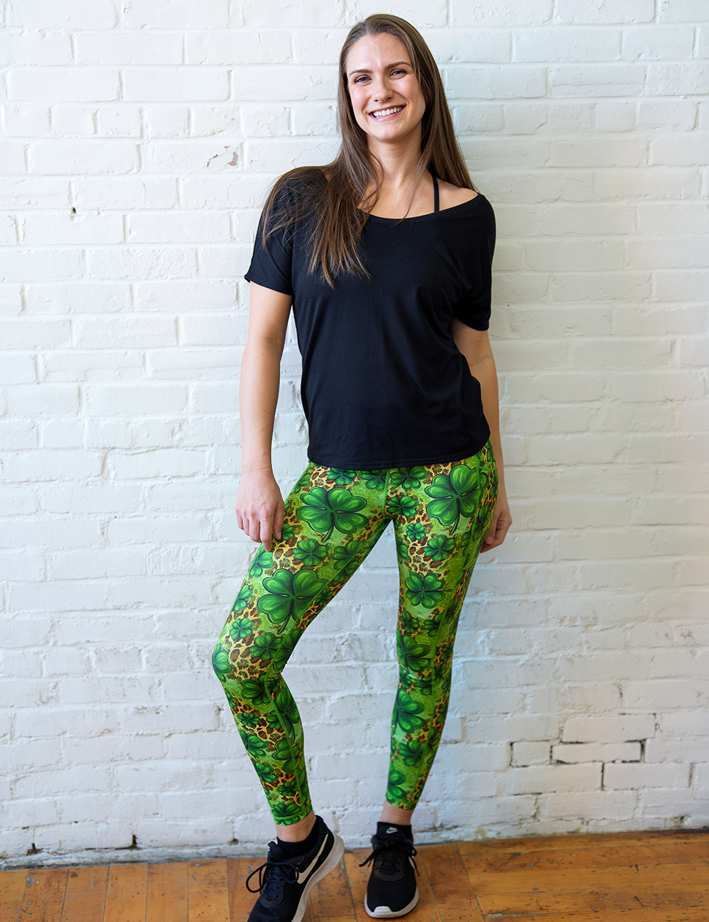 model wearing the clover pattern against a cheetah print and green background full length leggings against a white brick background