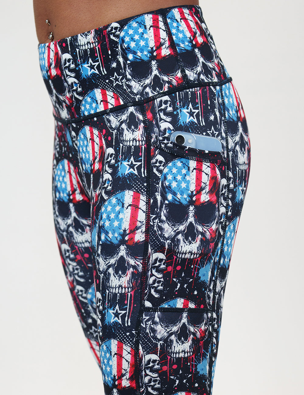 close up of the black leggings with american flag skulls with a phone in its pocket