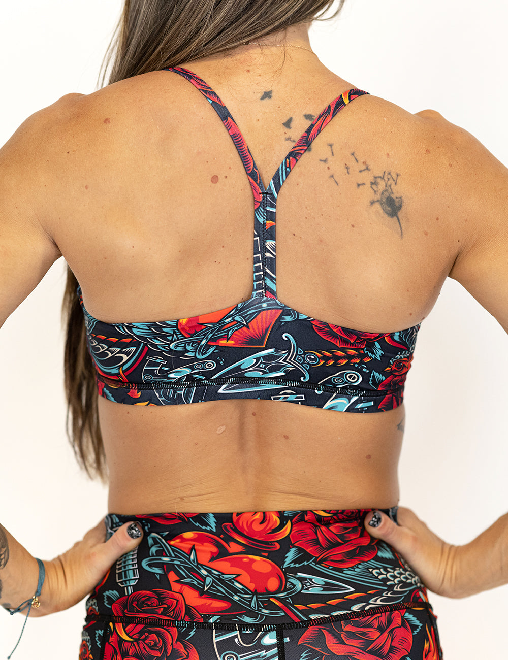 back view of criss cross strap design on rose and heart tattoo style patterned bra