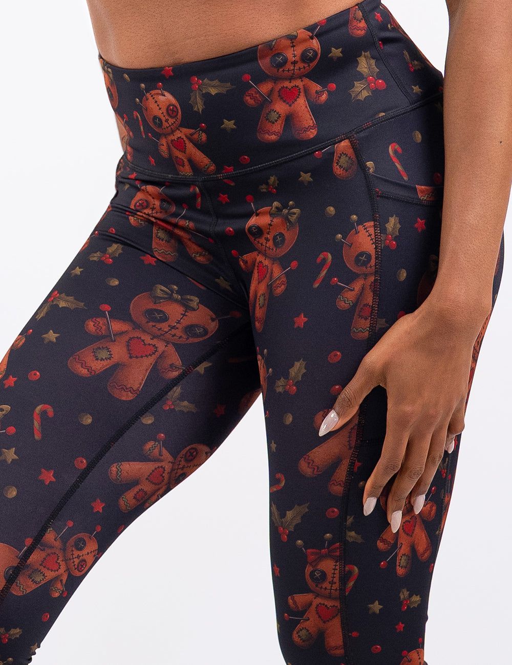 front of the gingerbread voodoo dolls with pins in them surrounded by berries and stars on a black background leggings