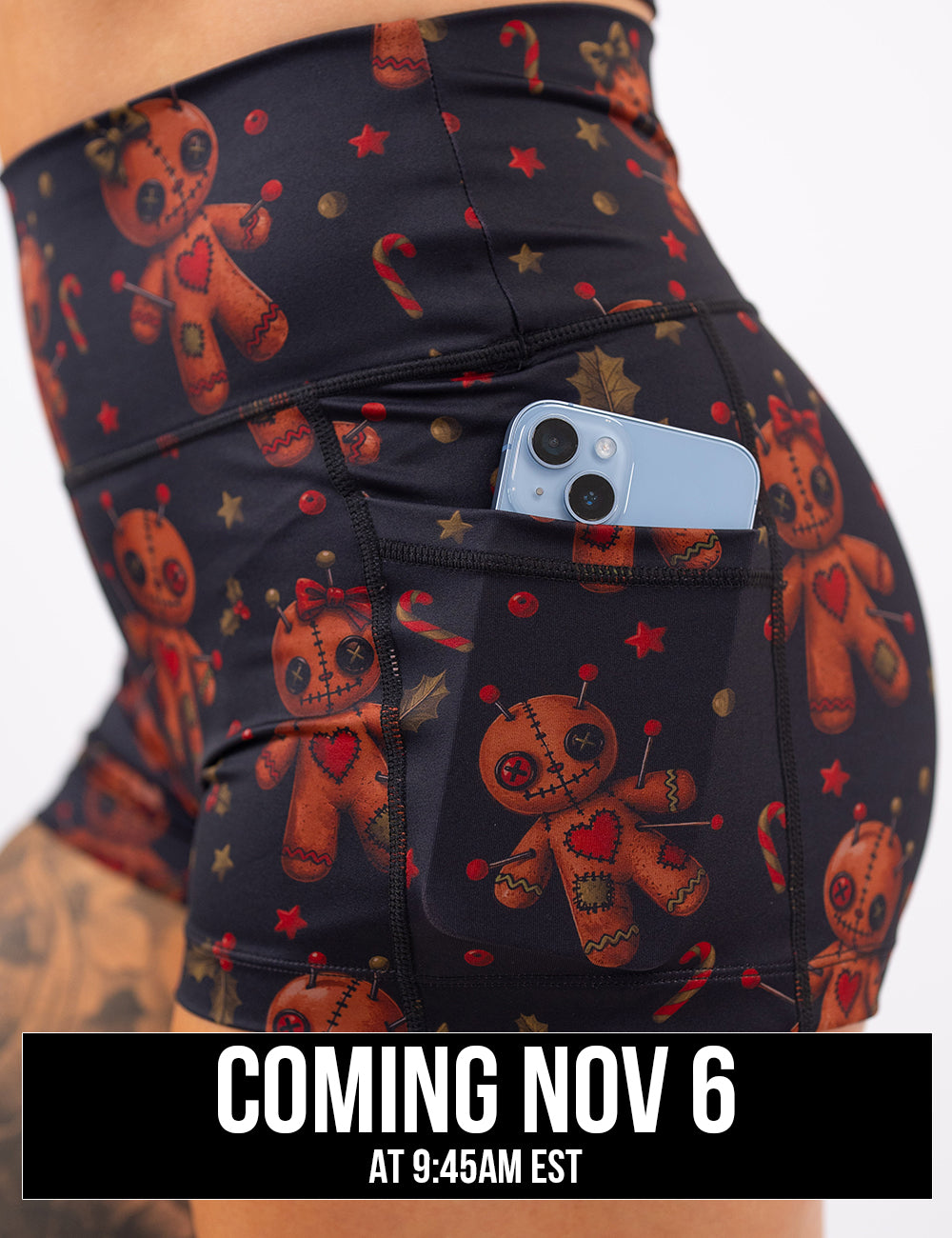 close up of the gingerbread voodoo dolls with pins in them surrounded by berries and stars on a black background 2.5 inch shorts with a phone in its pocket coming November 6th