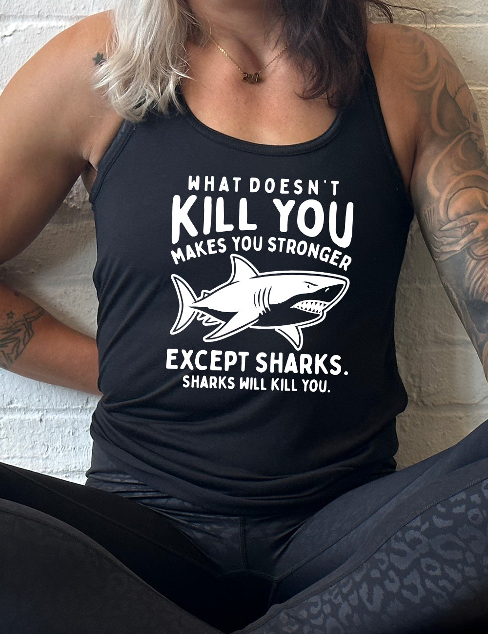 black racerback flowy tank with the words "what doesn't kill you makes you stronger except sharks. sharks will kill you." and the graphic of a fierce shark in the middle