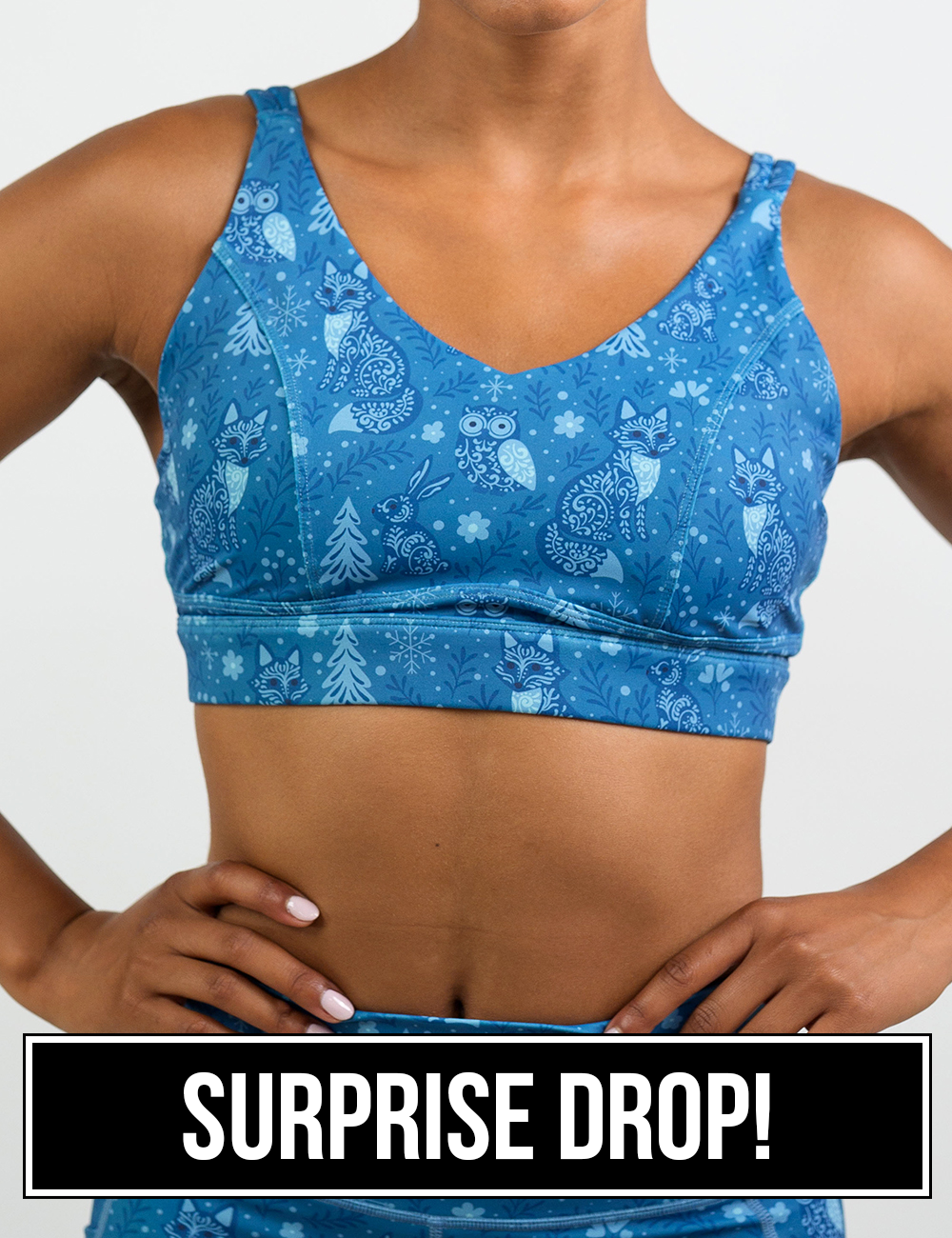 front of the blue foxes, owls, and bunnies in a winter landscape sports bra, surprise drop
