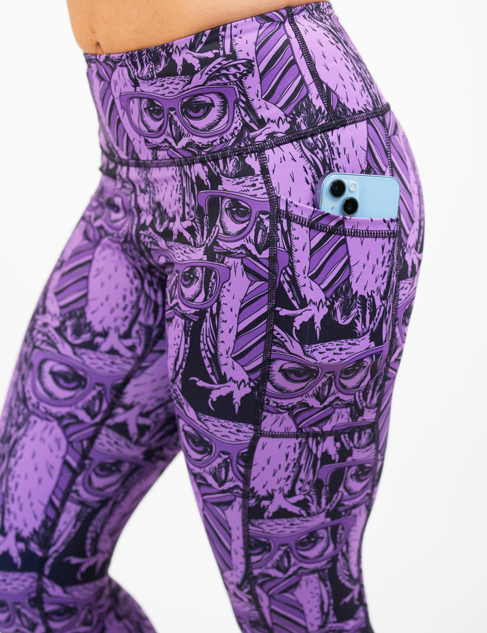 close up of the purple owl wearing glasses and a tie print leggings against a white background