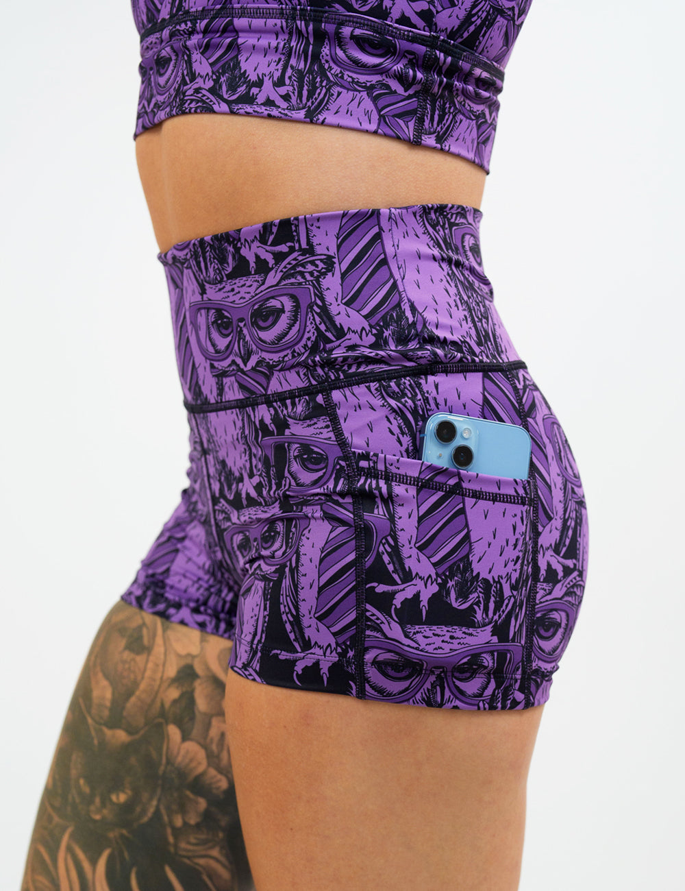 close up of the 2.5 inch purple owl wearing glasses and a tie print shorts against a white background