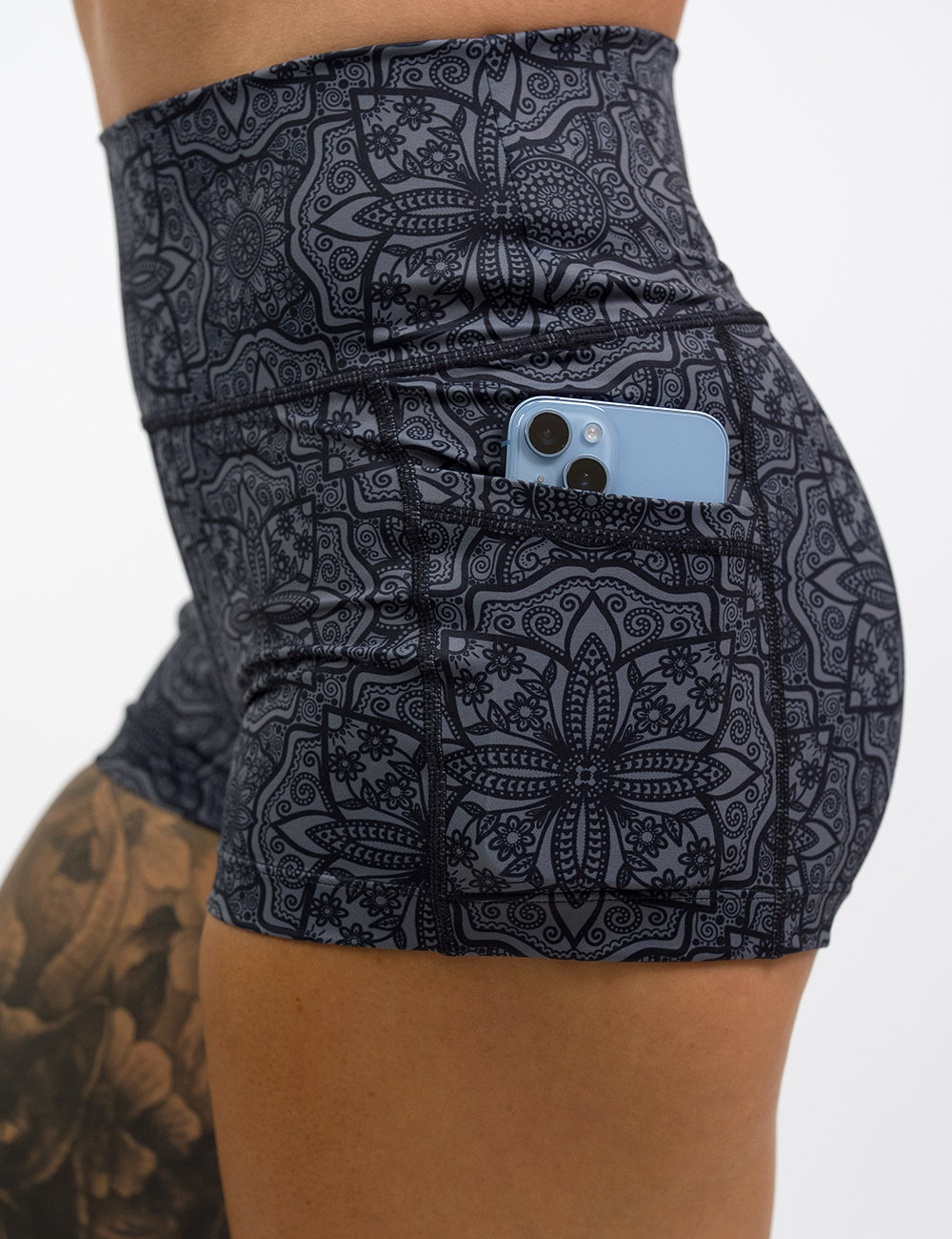 close up of the 2.5 inch black mandala pattern shorts with a phone in its pockets