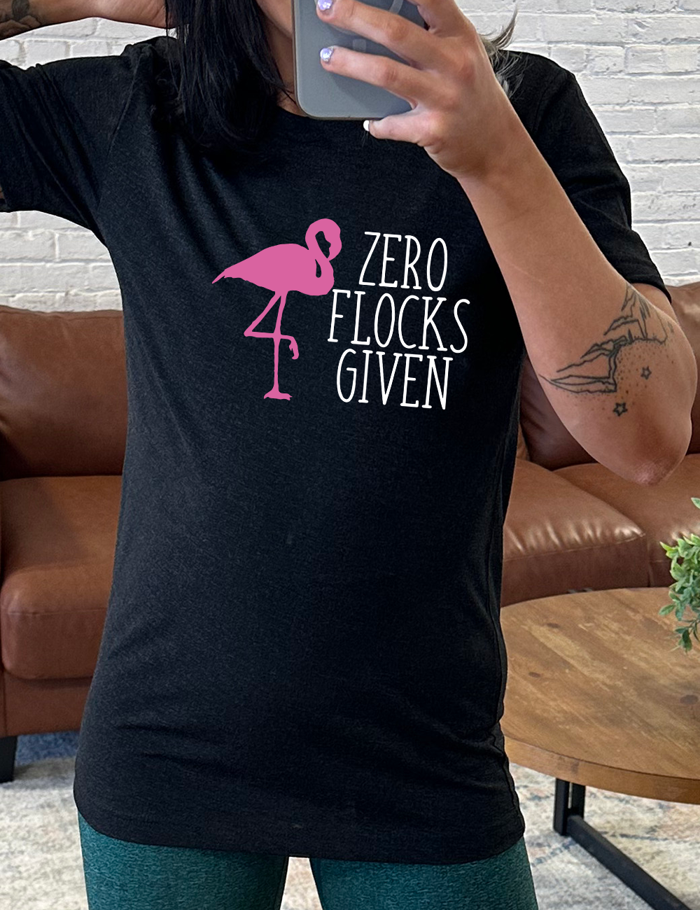 black unisex tee with the words "zero flocks given" on it, with the pink silhouette of a flamingo, leg raised, next to the words