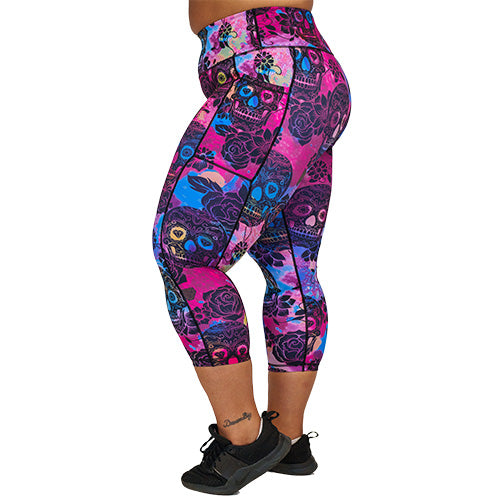side view of capri length purple, pink and blue tie dye leggings with black skull and rose pattern