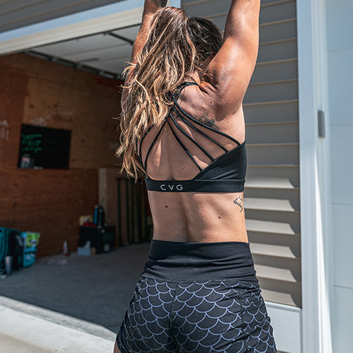 model wearing solid black sports bra and dragon scale shorts