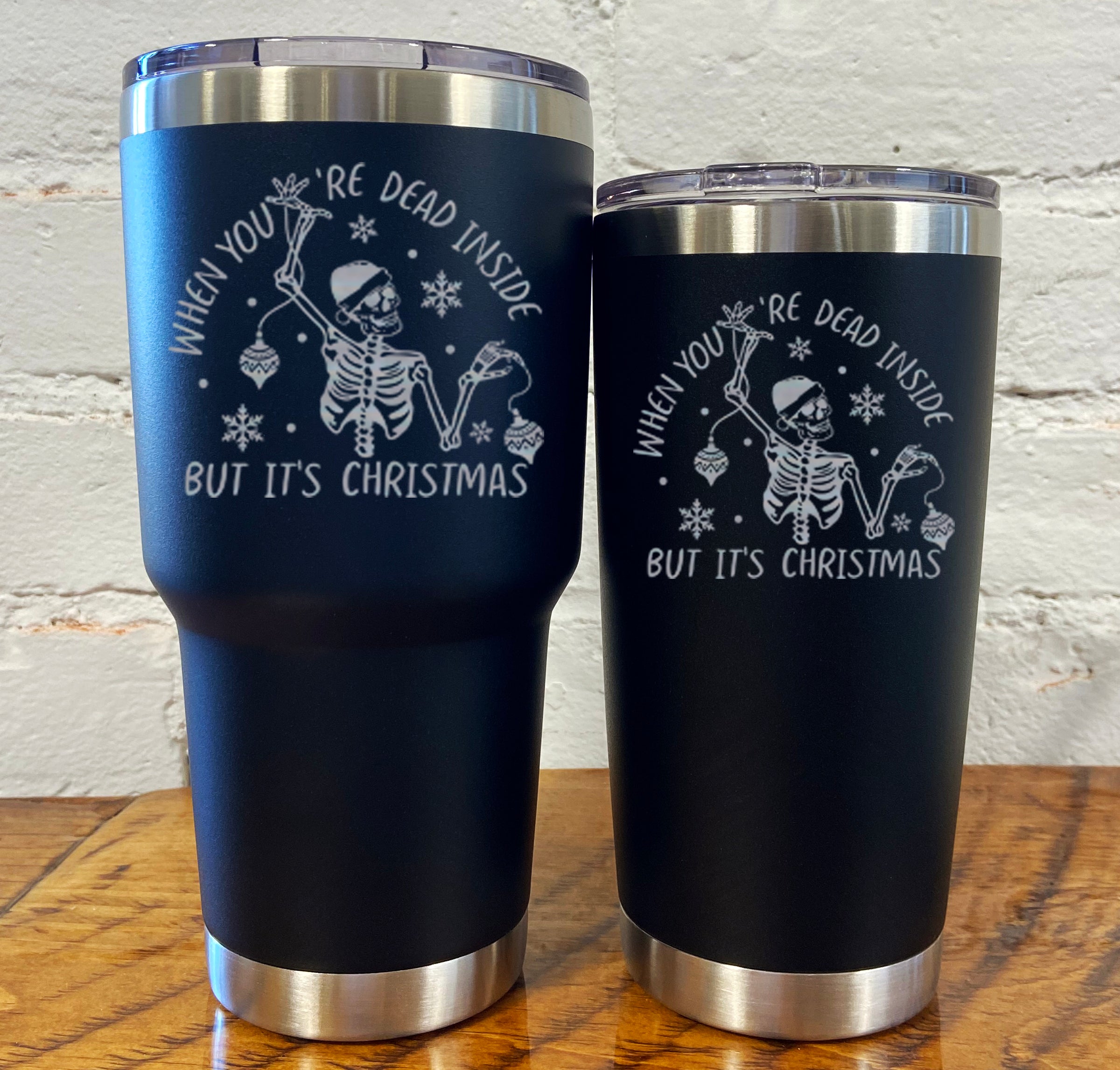 30oz and 20oz black tumblers with silver saying "when you're dead inside but it's christmas" with a santa hat skeleton holding ornaments